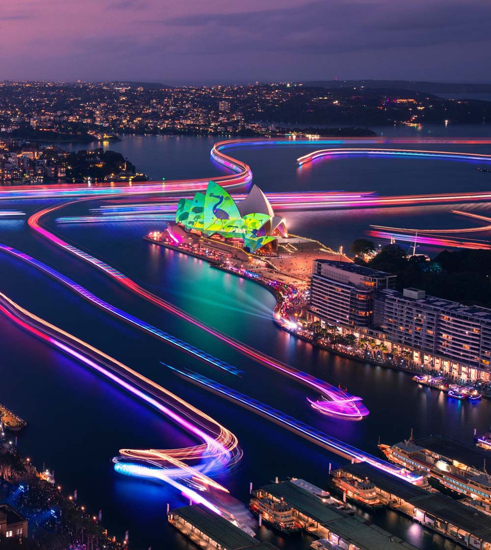 the lights of Vivid Sydney illuminating the harbour with boats