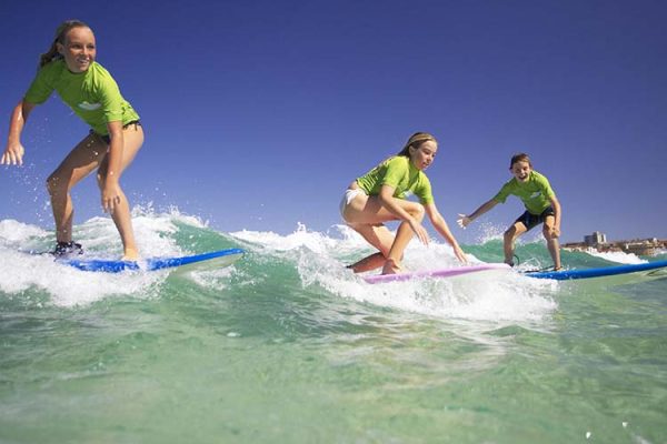 Kids surfing Bondi Beach as part of a surf lesson