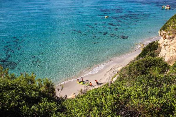 Aerial view of a secluded beach with a family on a kayak