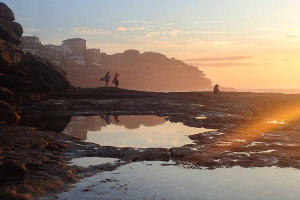 Sunrise view of the Tamarrama coastline as surfers head out